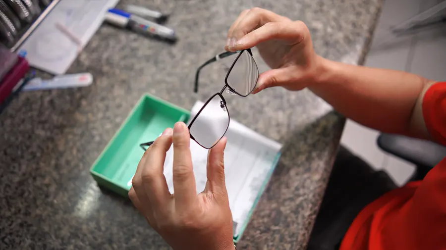 Técnica conferindo a armação e as lentes antes da entrega